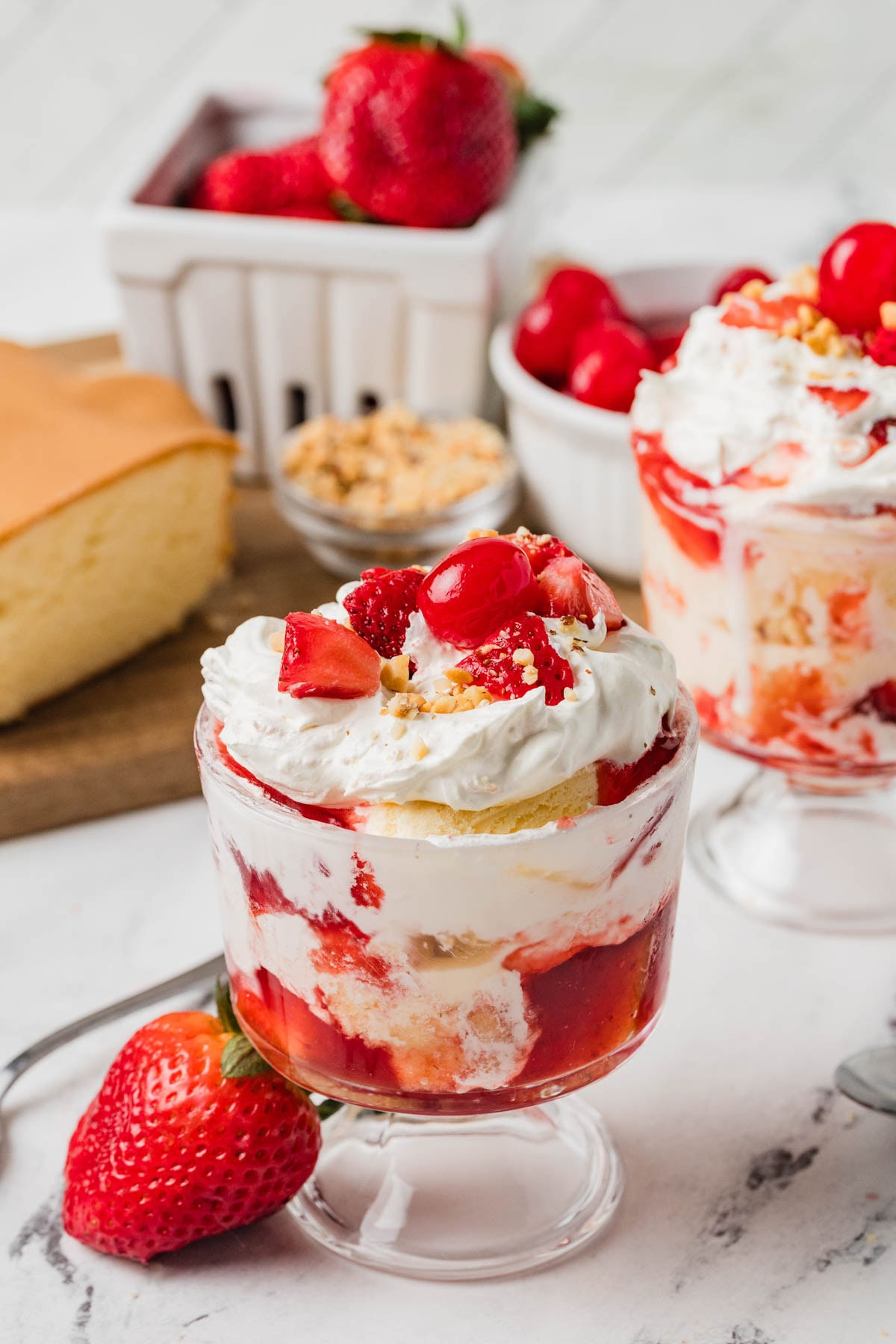 Strawberry shortcake ice cream sundae in a glass with layers of different ingredients.
