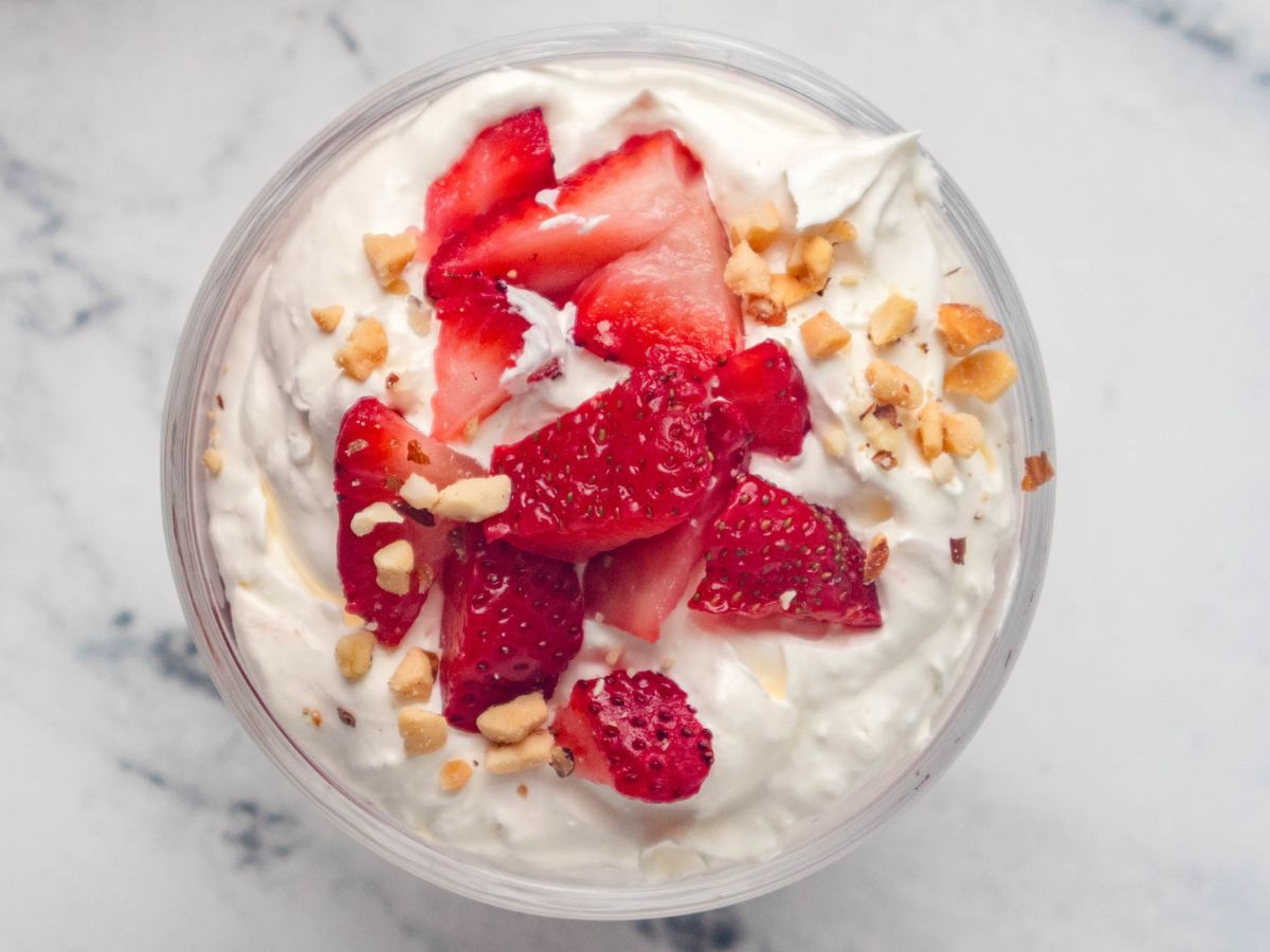 Adding chopped peanuts on top of the sliced strawberries.