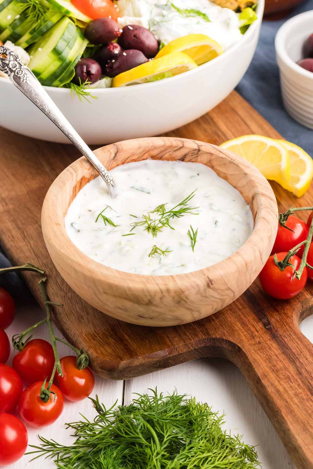 Tzatziki sauce served in a small wooden bowl with veggies around it.
