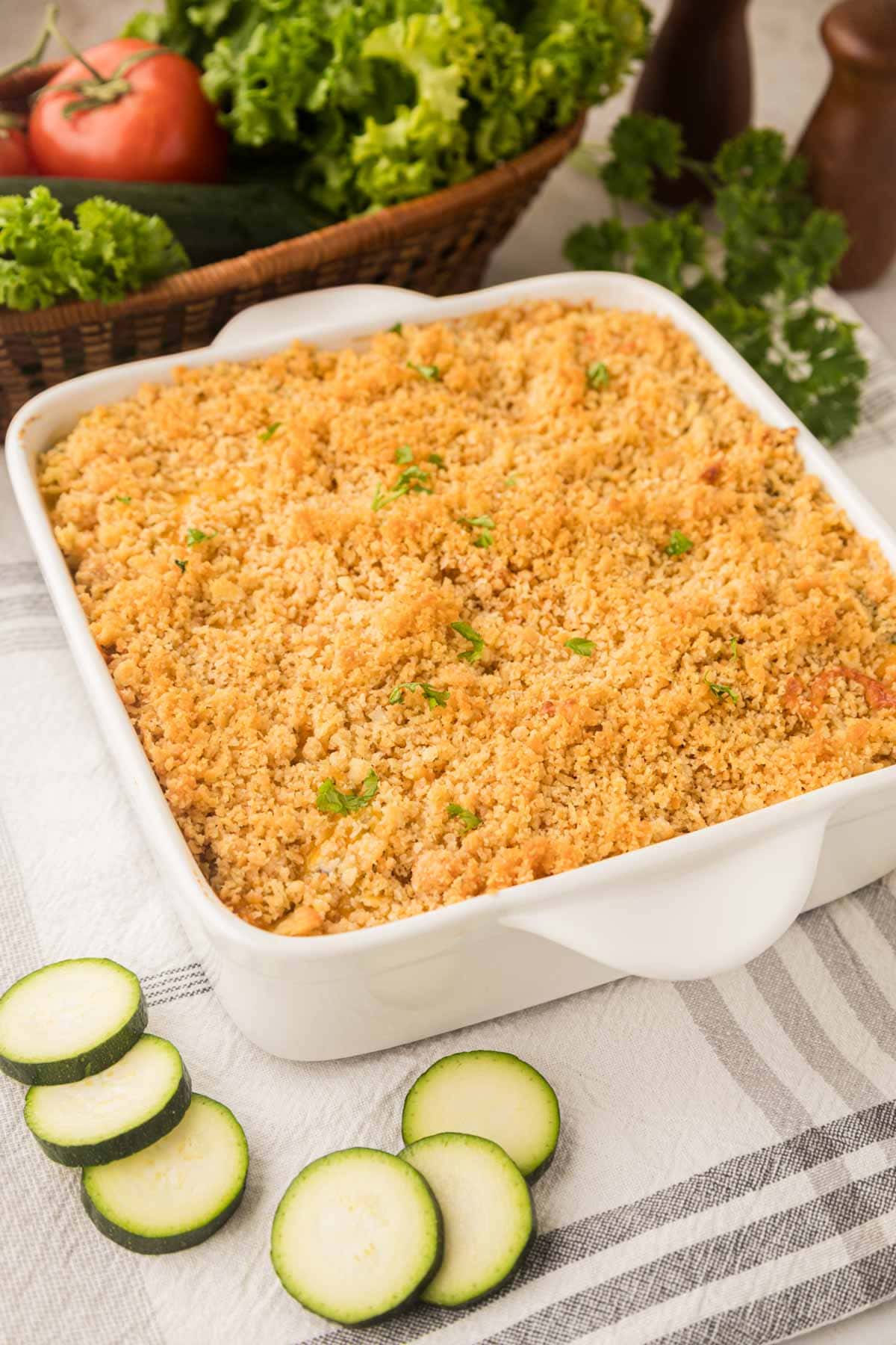 Zucchini casserole topped with a crunchy cracker topping in a white baking dish.