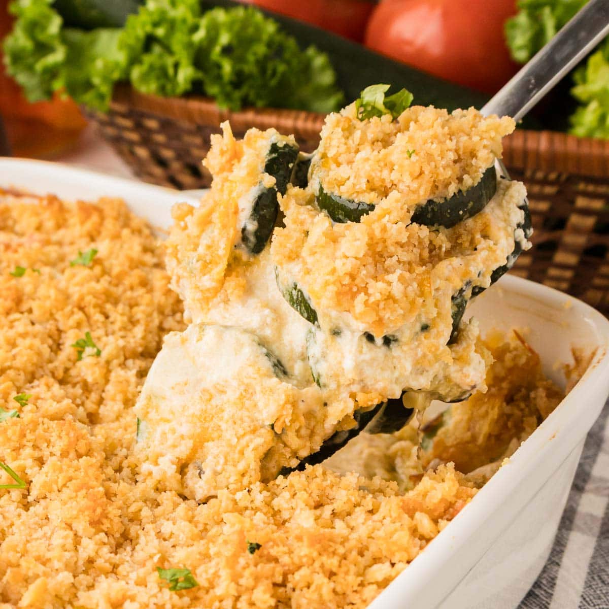 Spoon scooping up a portion of zucchini bake with the baking dish of casserole underneath it.