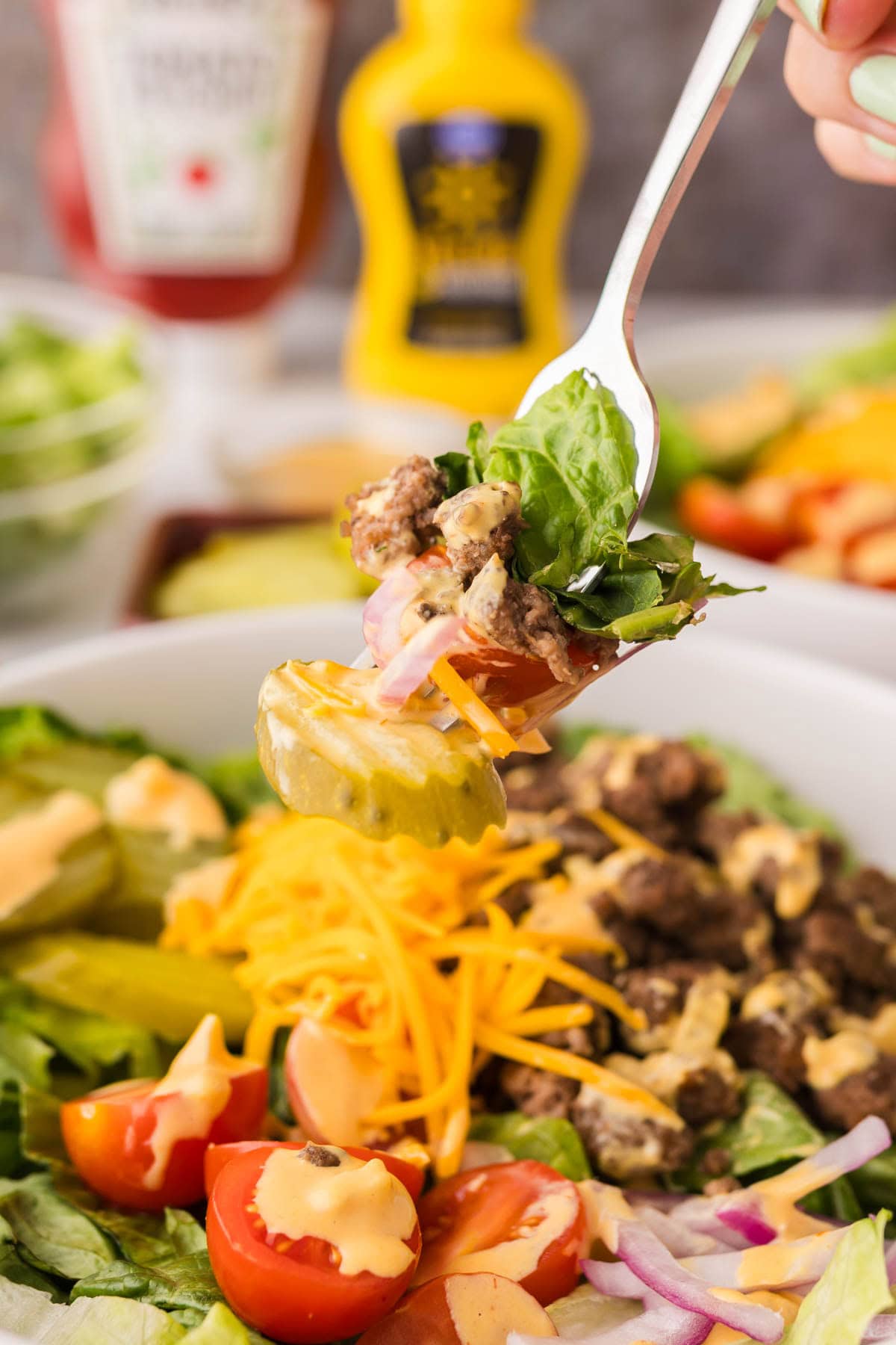 Fork with a bite of big mac salad on it with the salad below it.