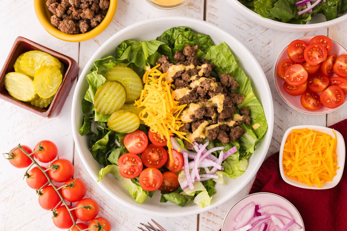 Overhead shot of assembled big mac salad in a white bowl.