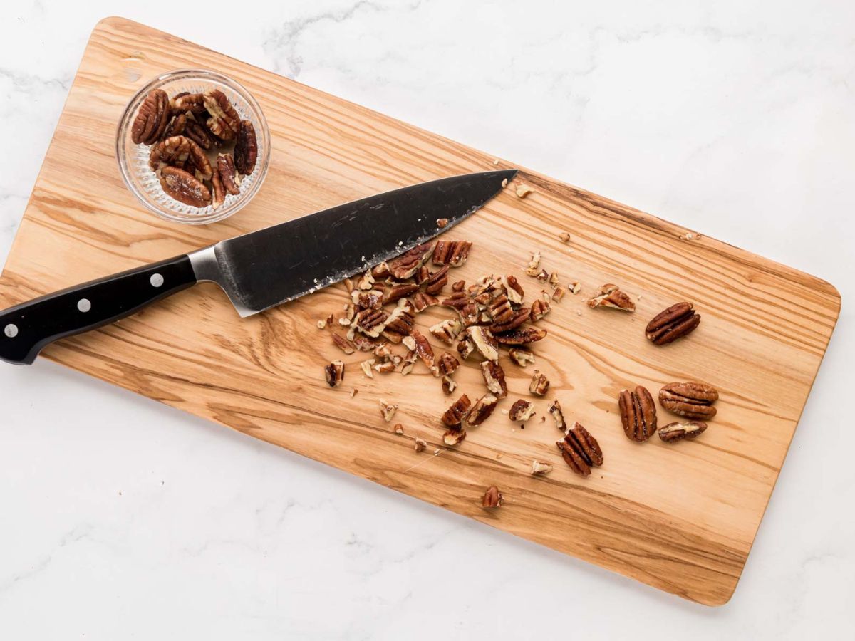 Chopped toasted pecans on a cutting board.