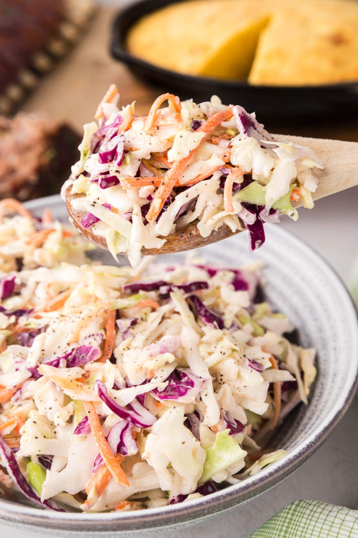 A spoon removing a scoop of coleslaw.