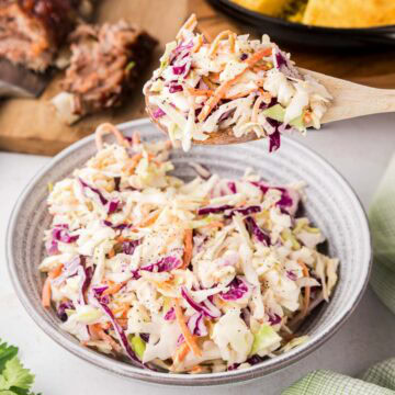 A spoon removing a scoop of coleslaw.