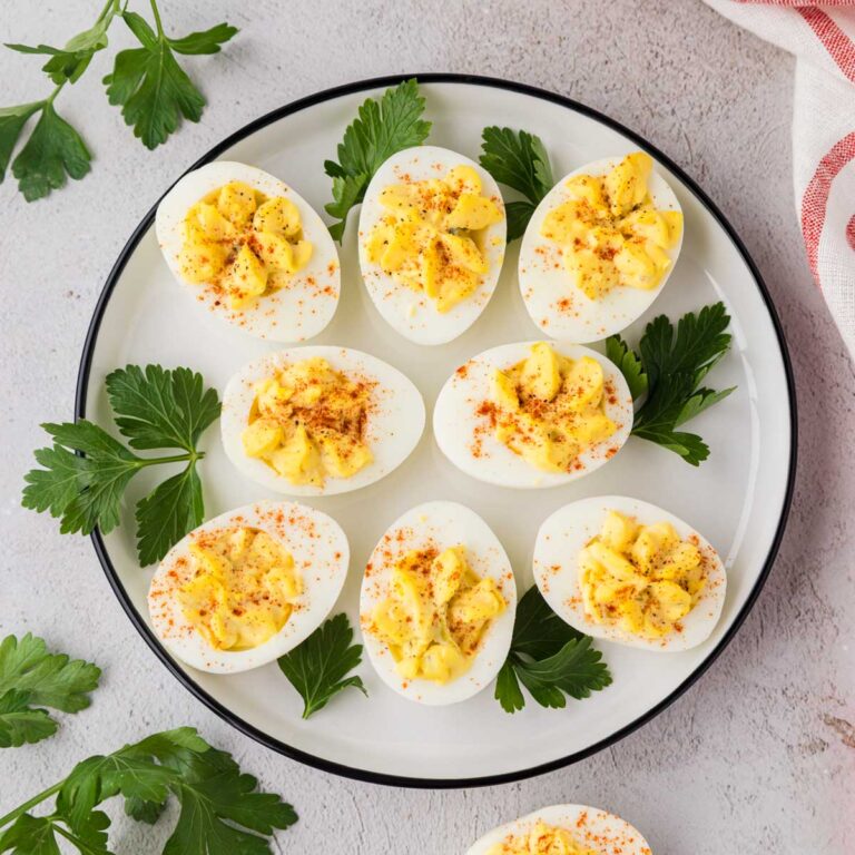 Deviled eggs on a white plate garnish with parsley.
