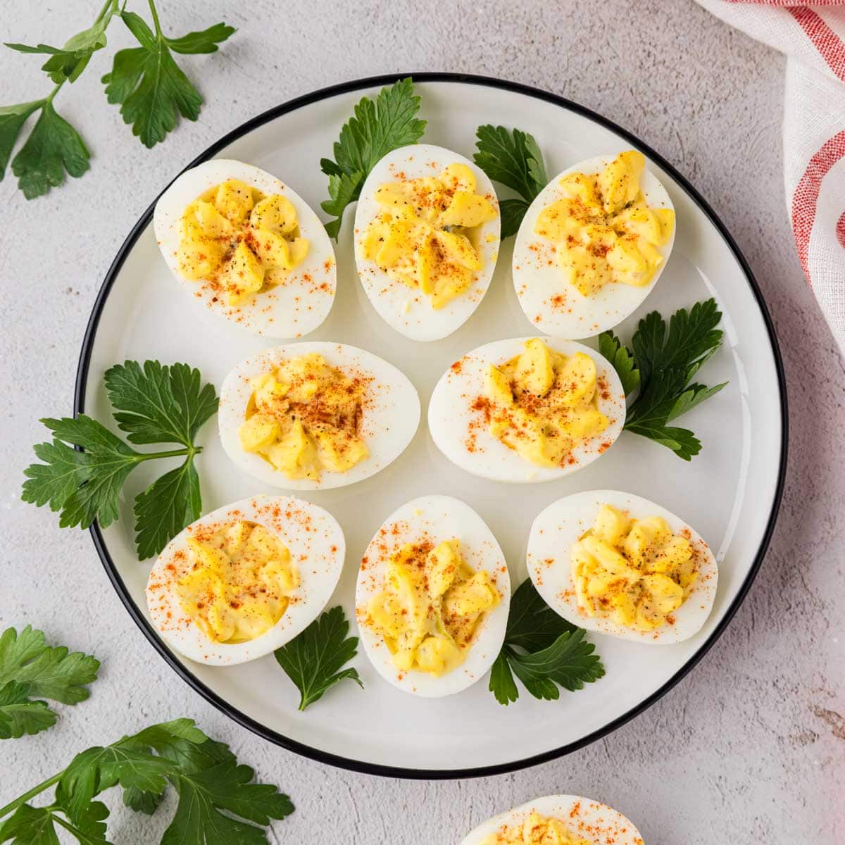Deviled eggs on a white plate garnish with parsley.