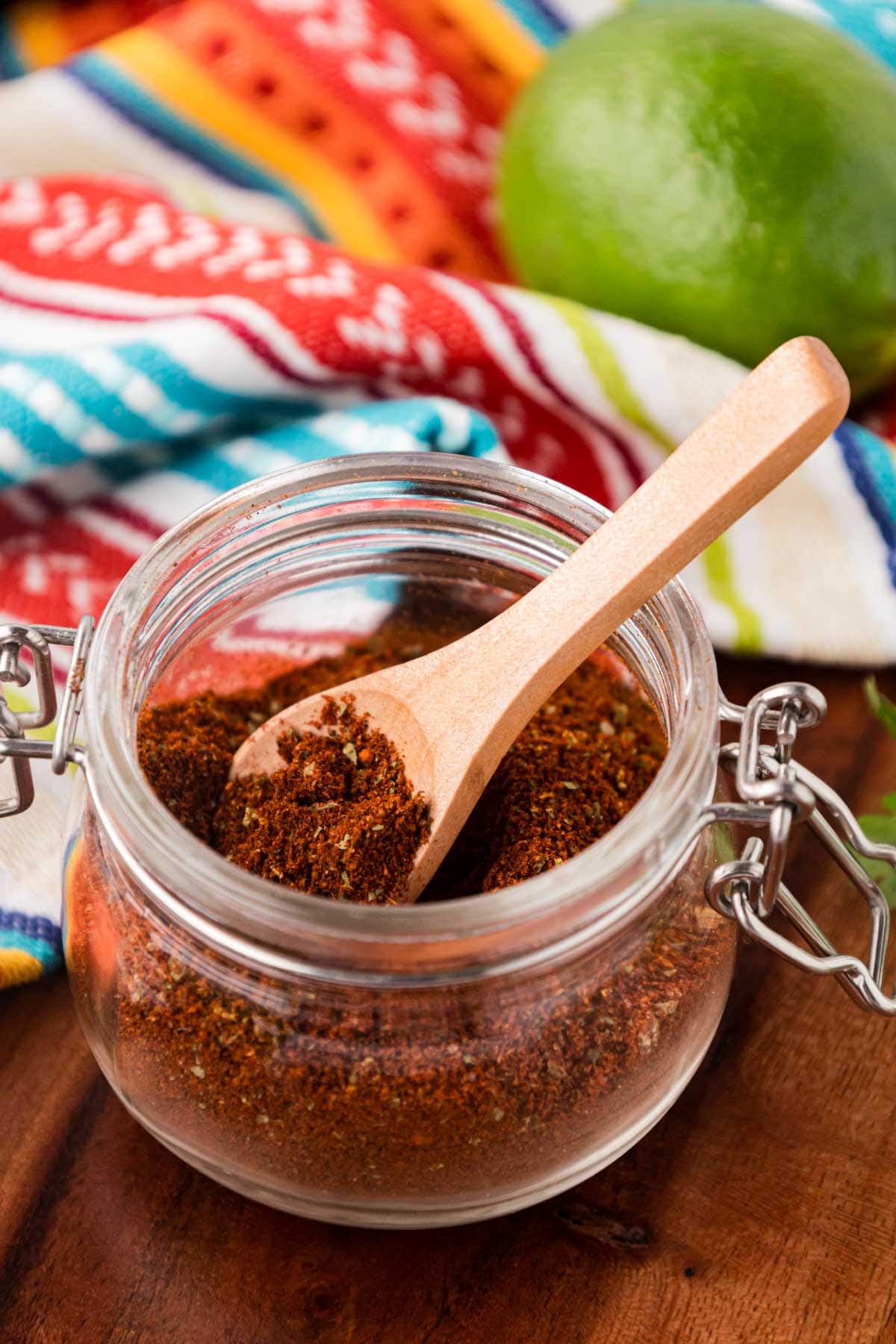 Homemade elote seasoning in a glass jar with a wooden spoon.