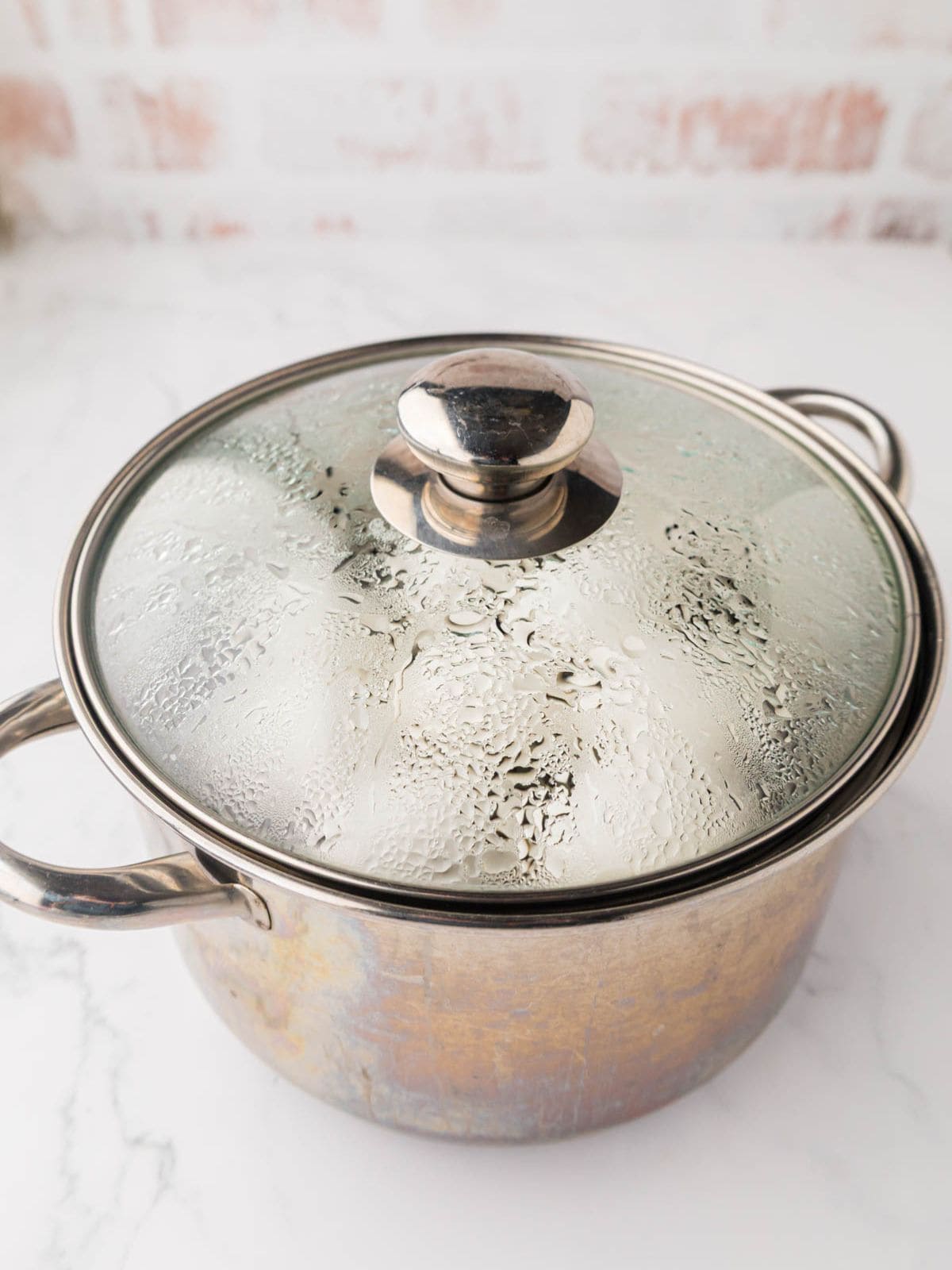 Eggs in a pot with a clear lid on top showing condensation from steaming.