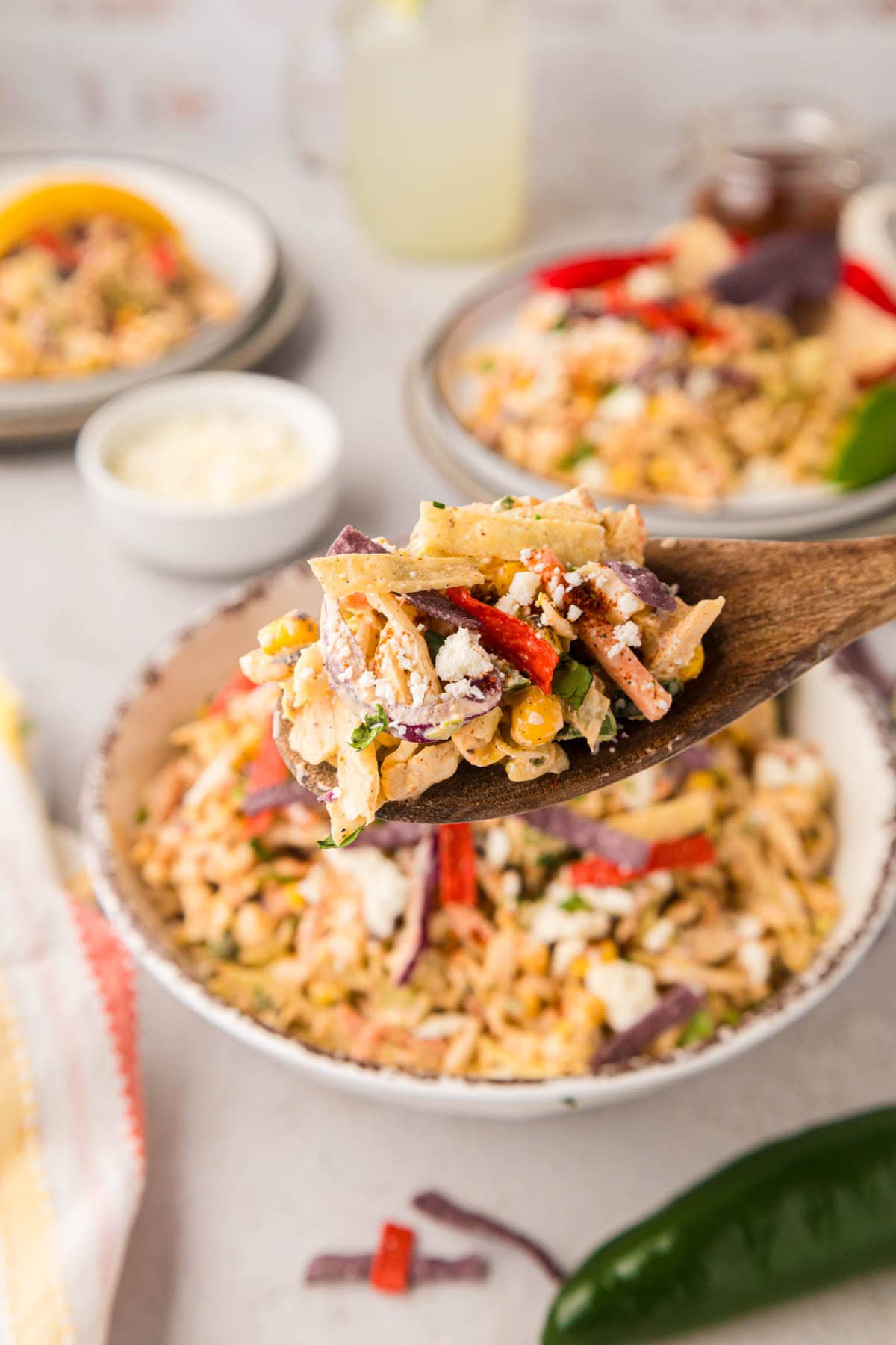 A wooden spoon removing a scoop of street corn slaw.