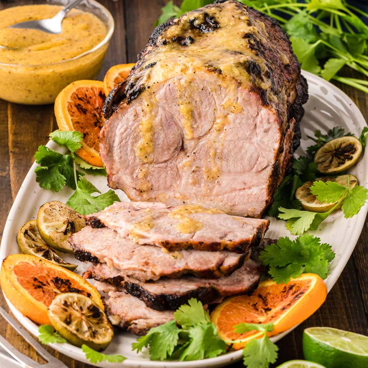 Cuban pork placed on a serving platter with slices of citrus and cilantro around it.