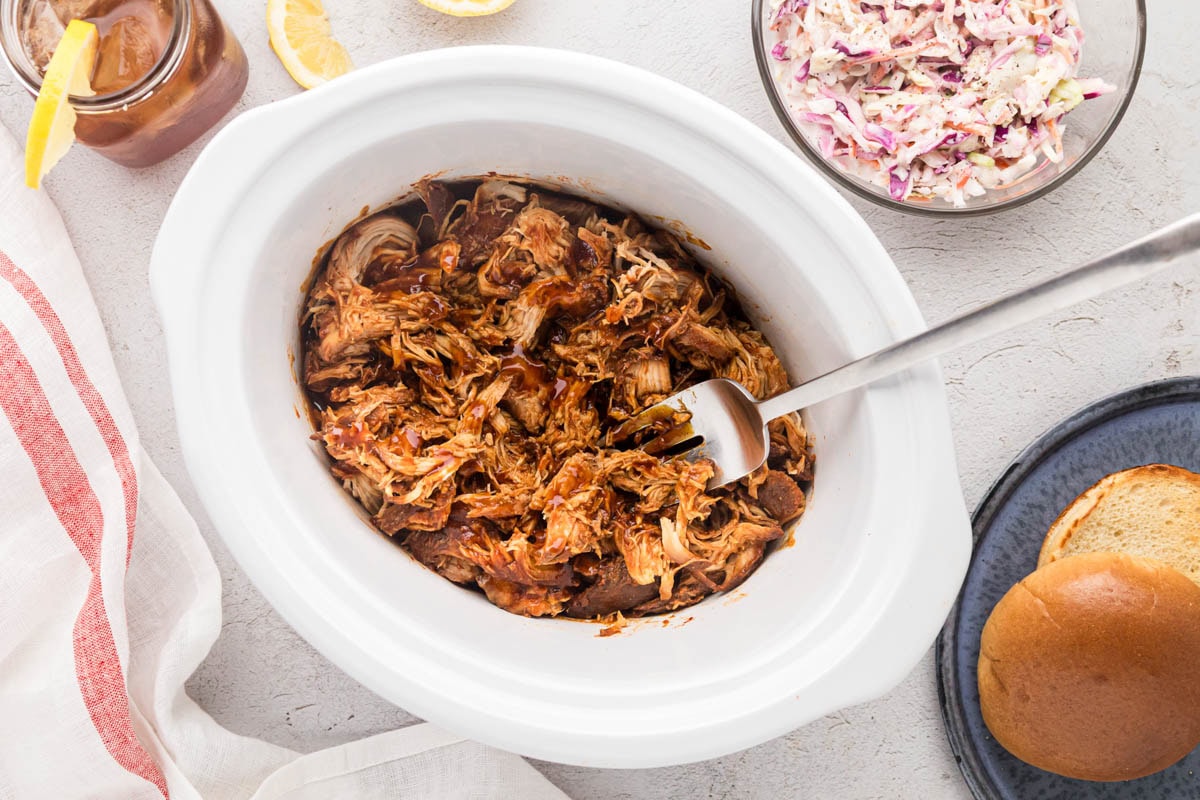 Overhead shot of pulled BBQ chicken in a slow cooker.