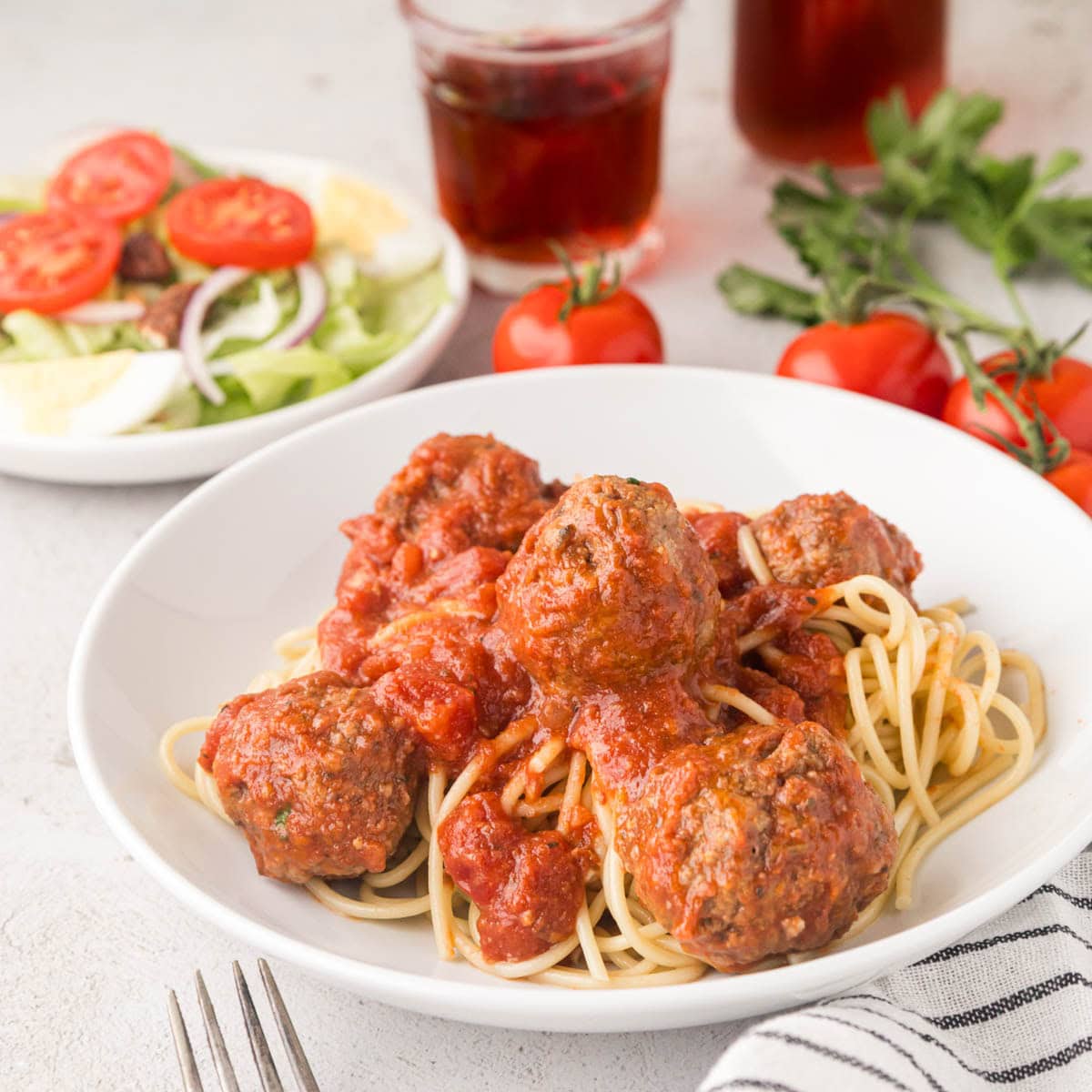 Bowl of spaghetti with slow cooker Italian meatballs and sauce on top.