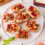 Overhead shot of strawberry bruschetta served on a white plate.
