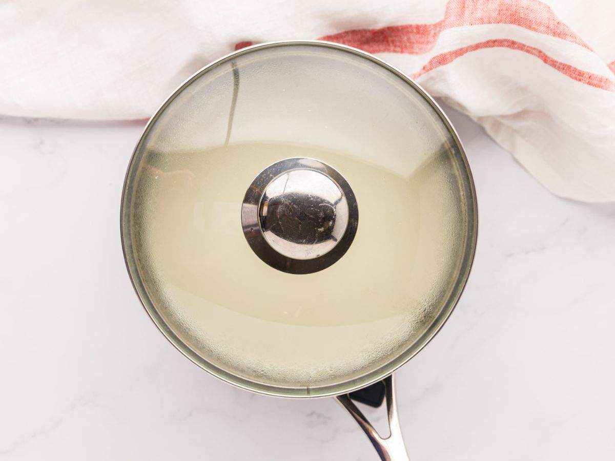 A lid on a saucepan of cooking grits.