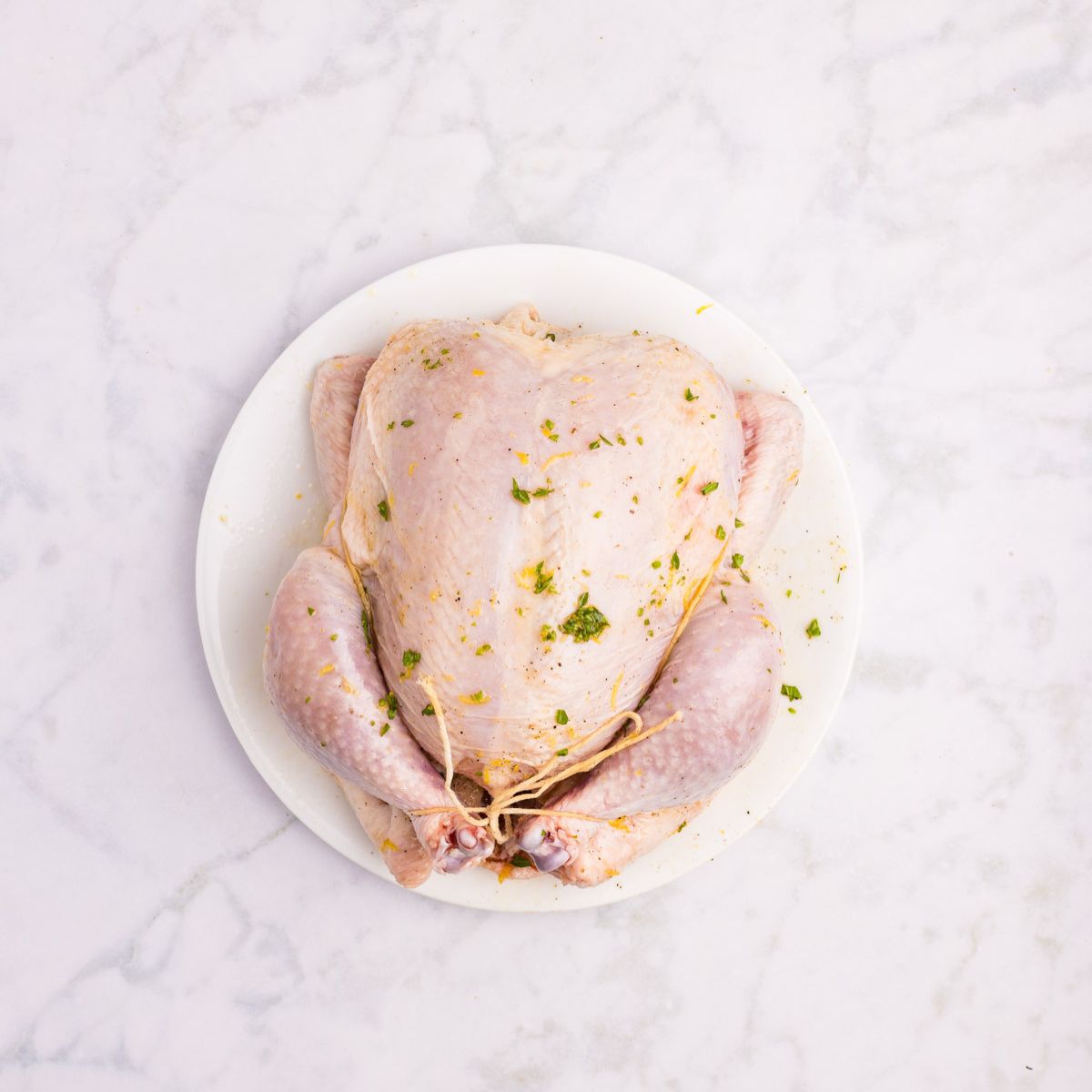 Raw chicken on a plate with the marinate on top.