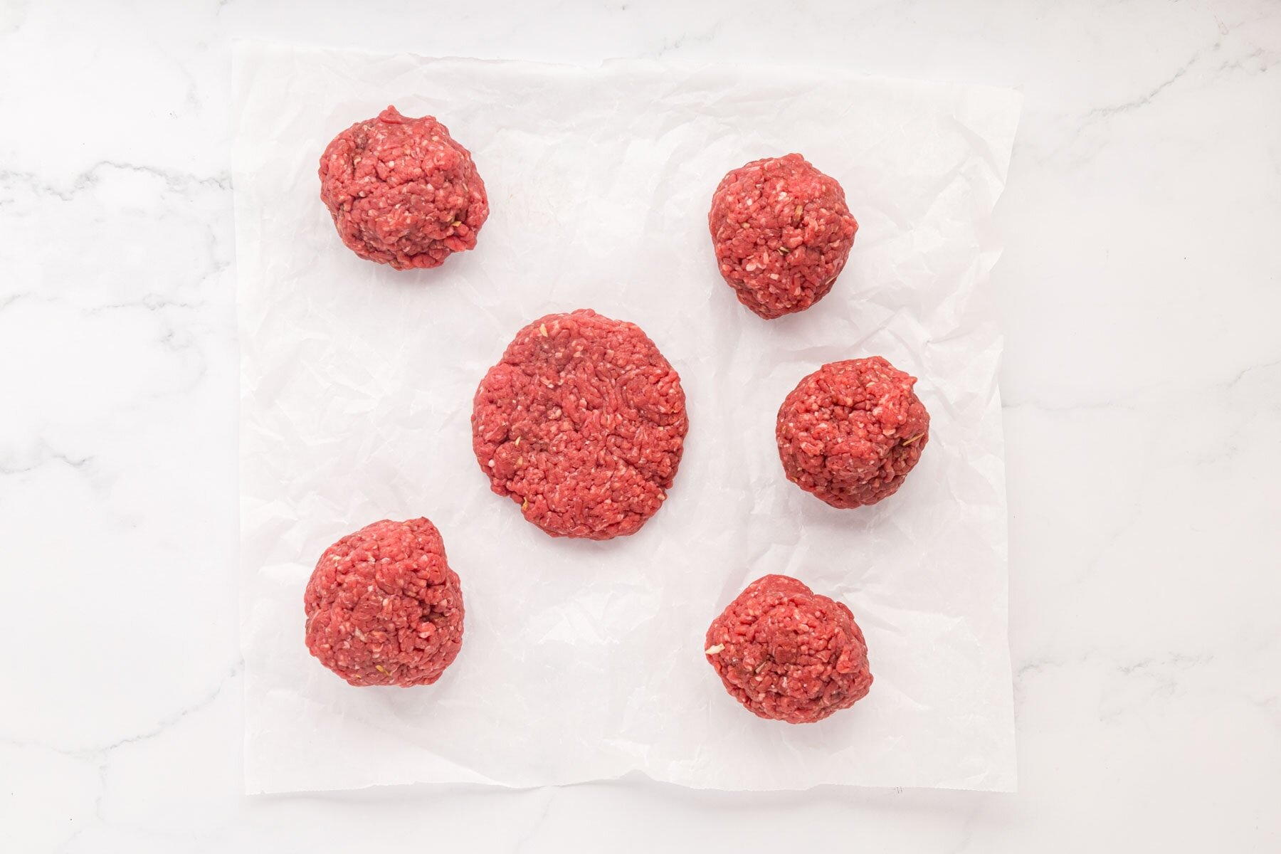 Hamburger patties on parchment paper.