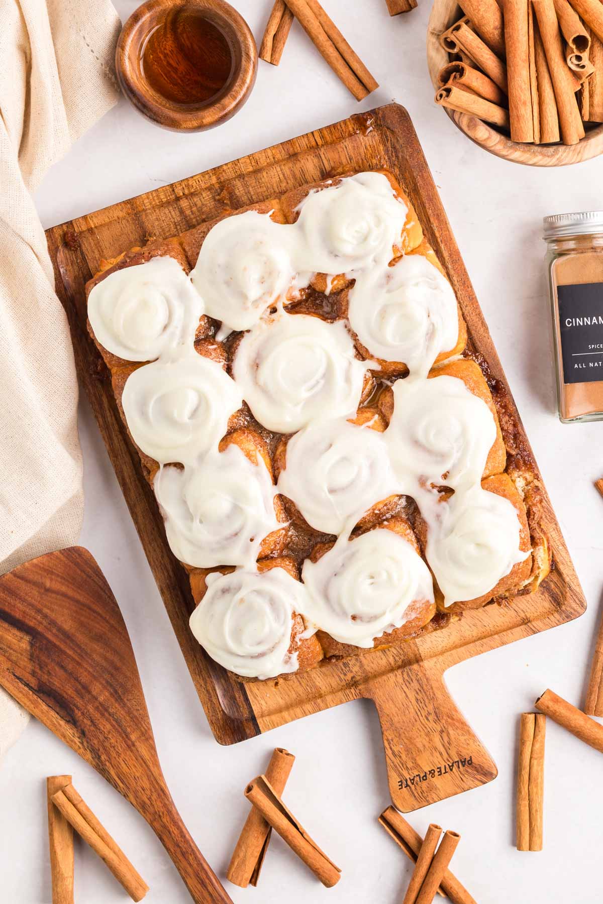Overhead shot of Hawaiian roll cinnamon rolls on a wooden board with cinnamon sticks around.
