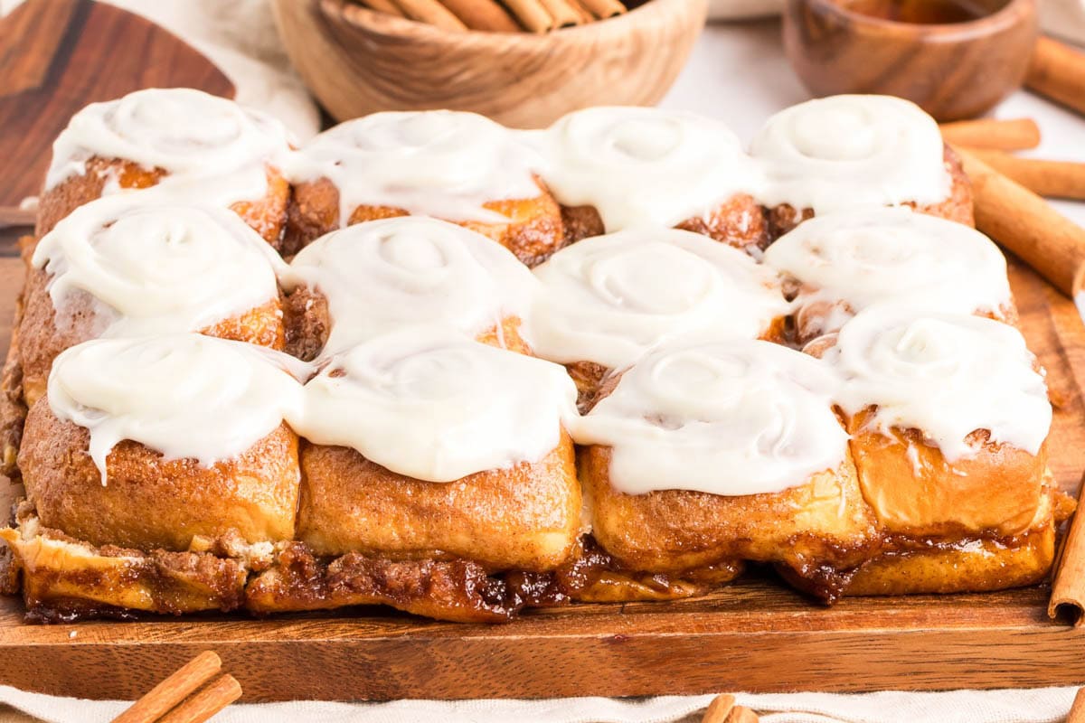 Side view of Hawaiian cinnamon rolls on a wooden board.
