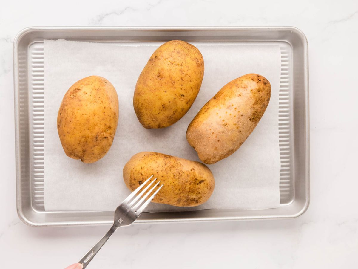 A fork piercing russet potatoes.