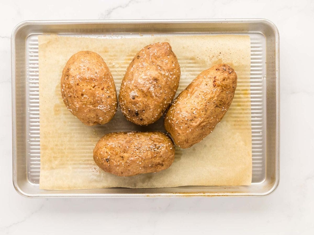 Roasted baked potatoes after being baked on a baking sheet.