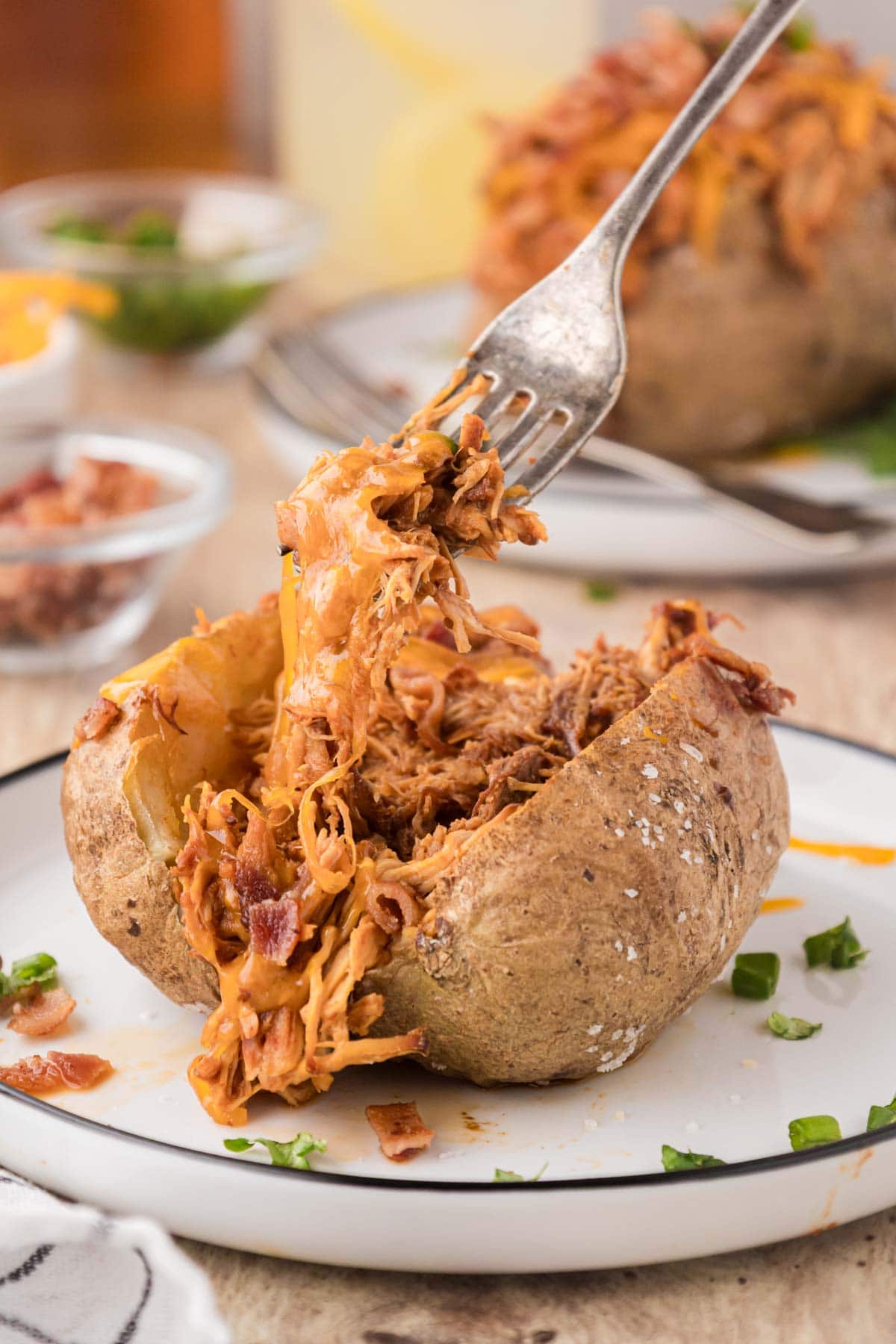 A fork, removing a bite of barbecue potato.