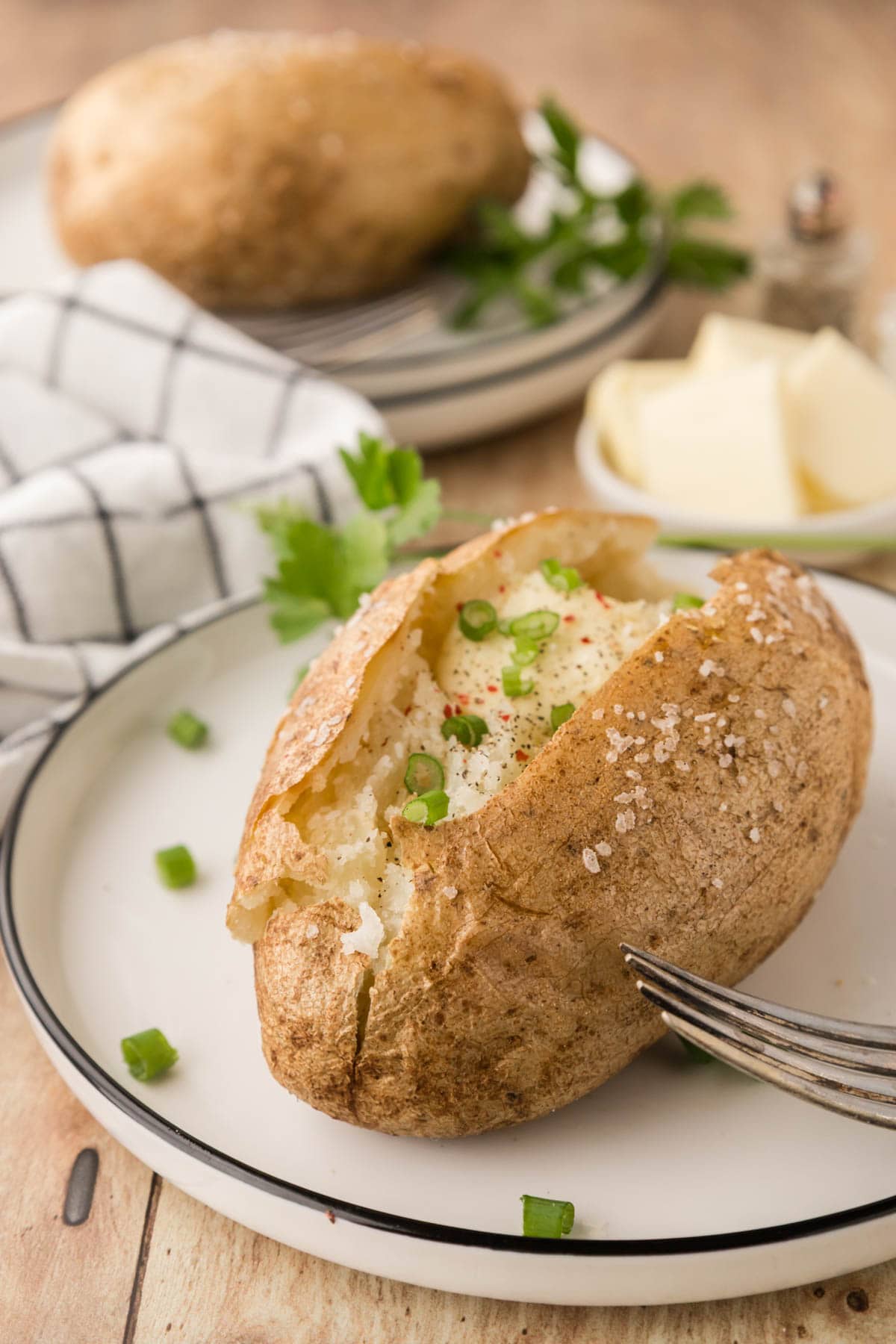 A baked potato garnished with chives and sprinkled with red pepper.