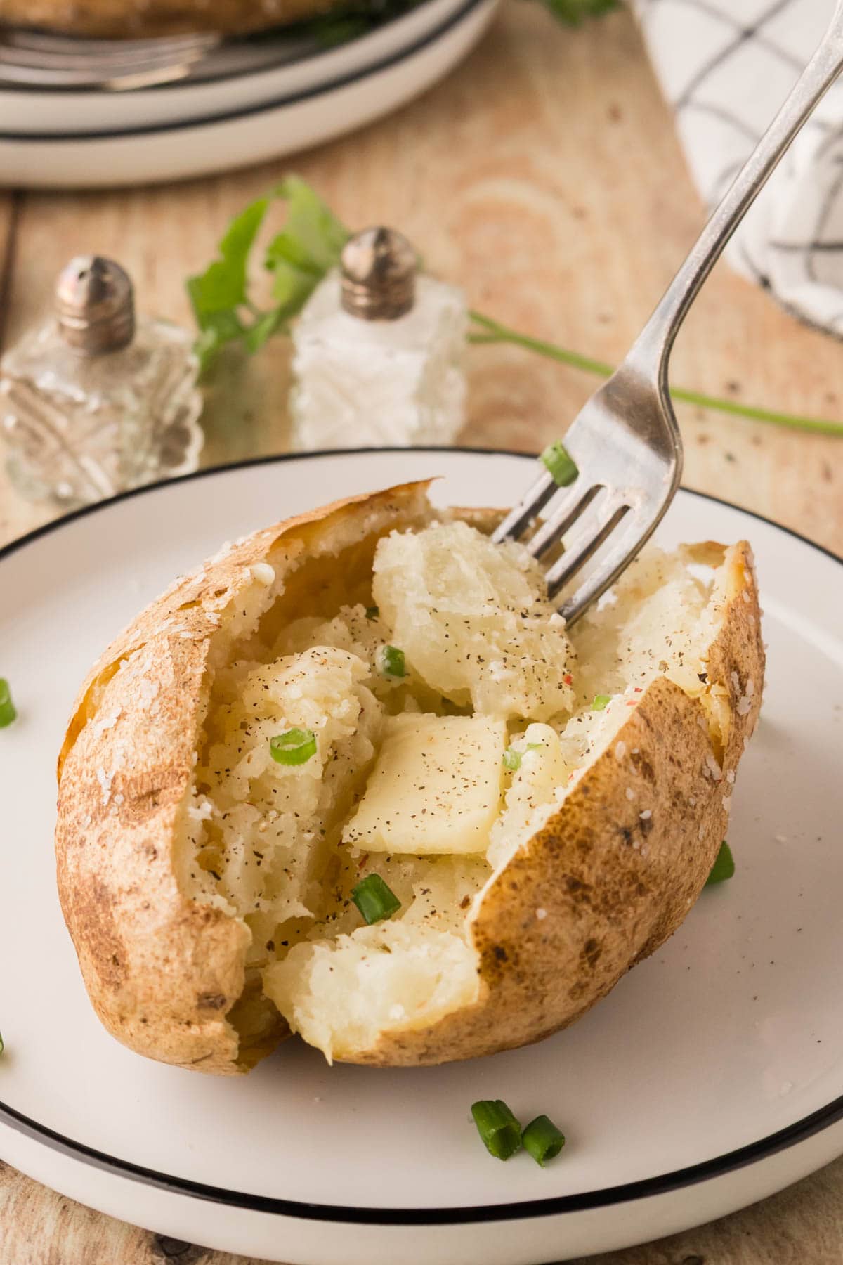 A fork fluffing the inside of a baked potato.