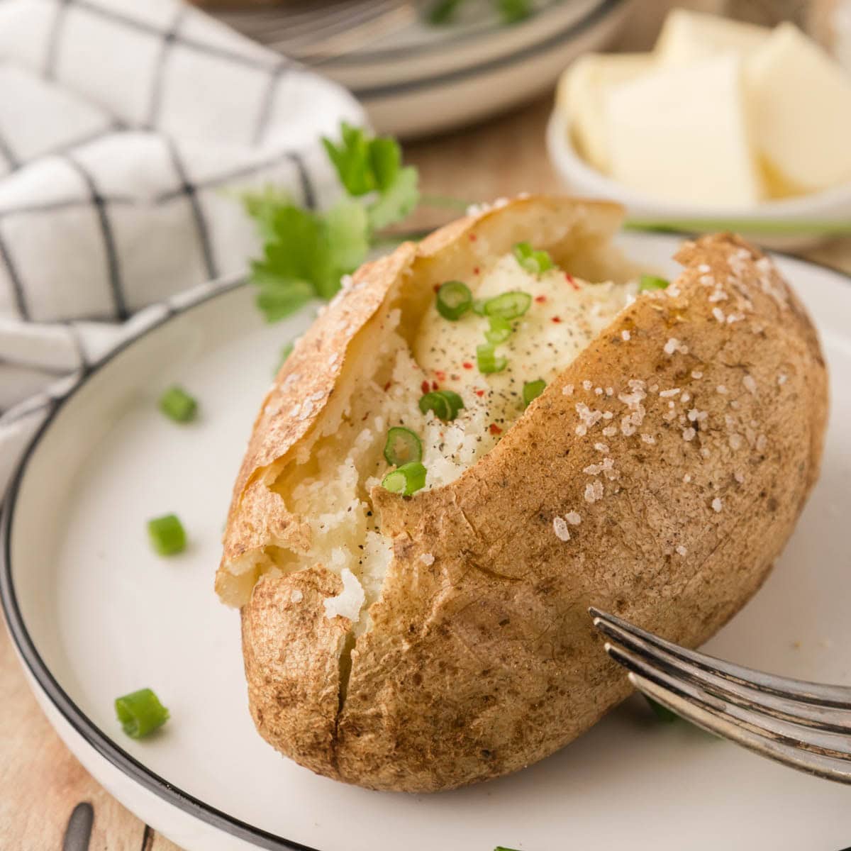 A baked potato garnished with chives and sprinkled with red pepper.
