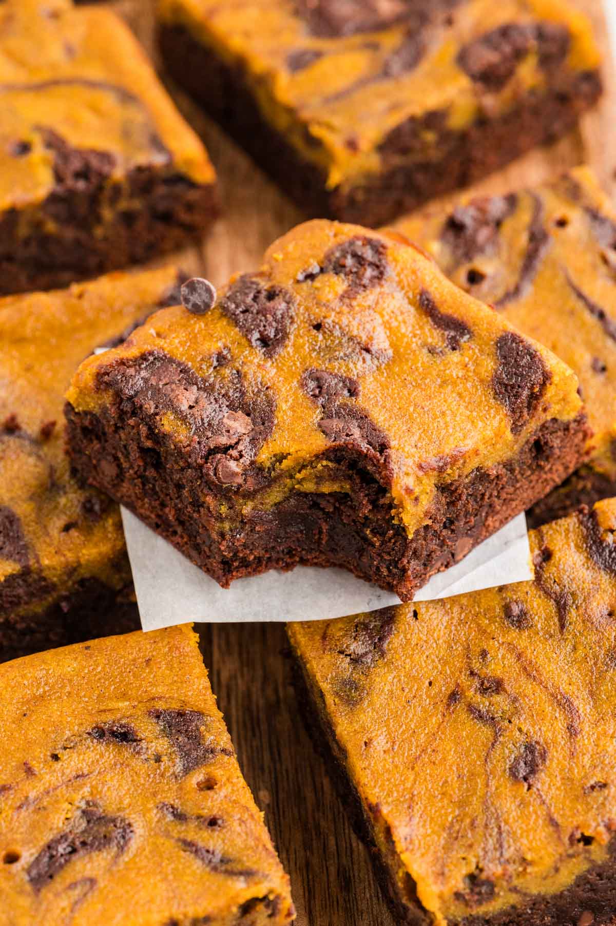 Pumpkin brownie with a bite taken out of it on more pumpkin brownies lined up underneath it.
