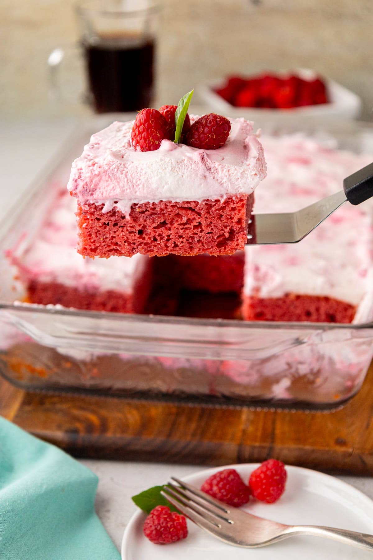 A serving spatula, removing a slice of raspberry fluff cake from the pan.