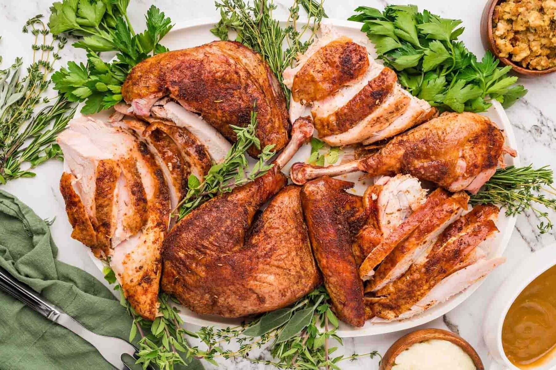 Smoked spatchcocked turkey broked down into different pieces and served on a serving dish.