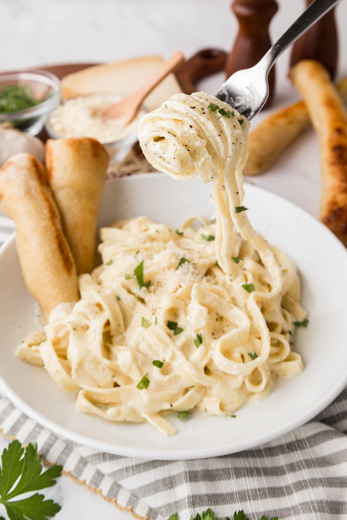 Fettuccine noodles coated, and homemade Alfredo sauce twirled on a fork.