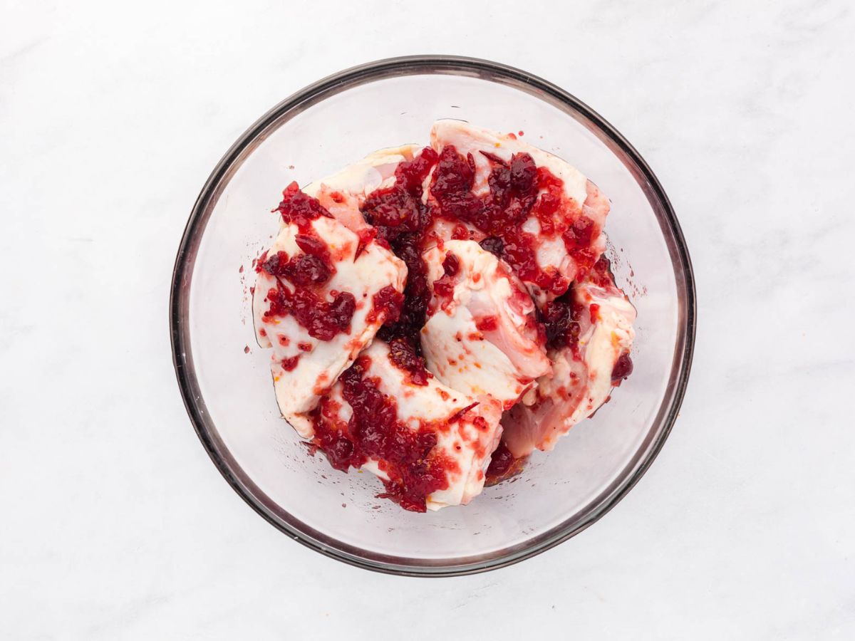 Marinating the chicken thighs in the cranberry marinade.