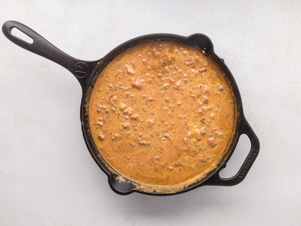 Melted velveeta with ground beef queso in a skillet.