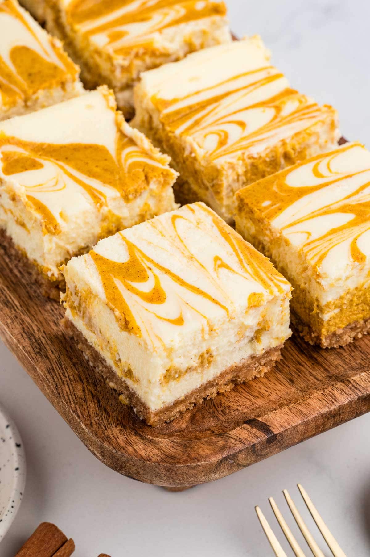 Pumpkin swirl cheesecake bars on a wooden board.