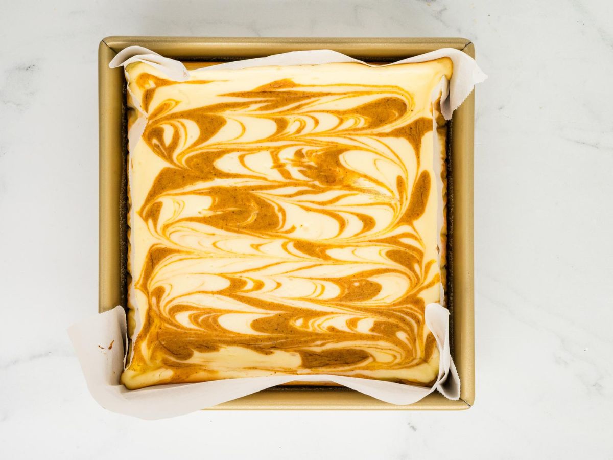 Baked pumpkin cheesecake bars in the baking dish before slicing them.