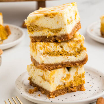 Side view of three pumpkin cheesecake bars stacked on top of each other.