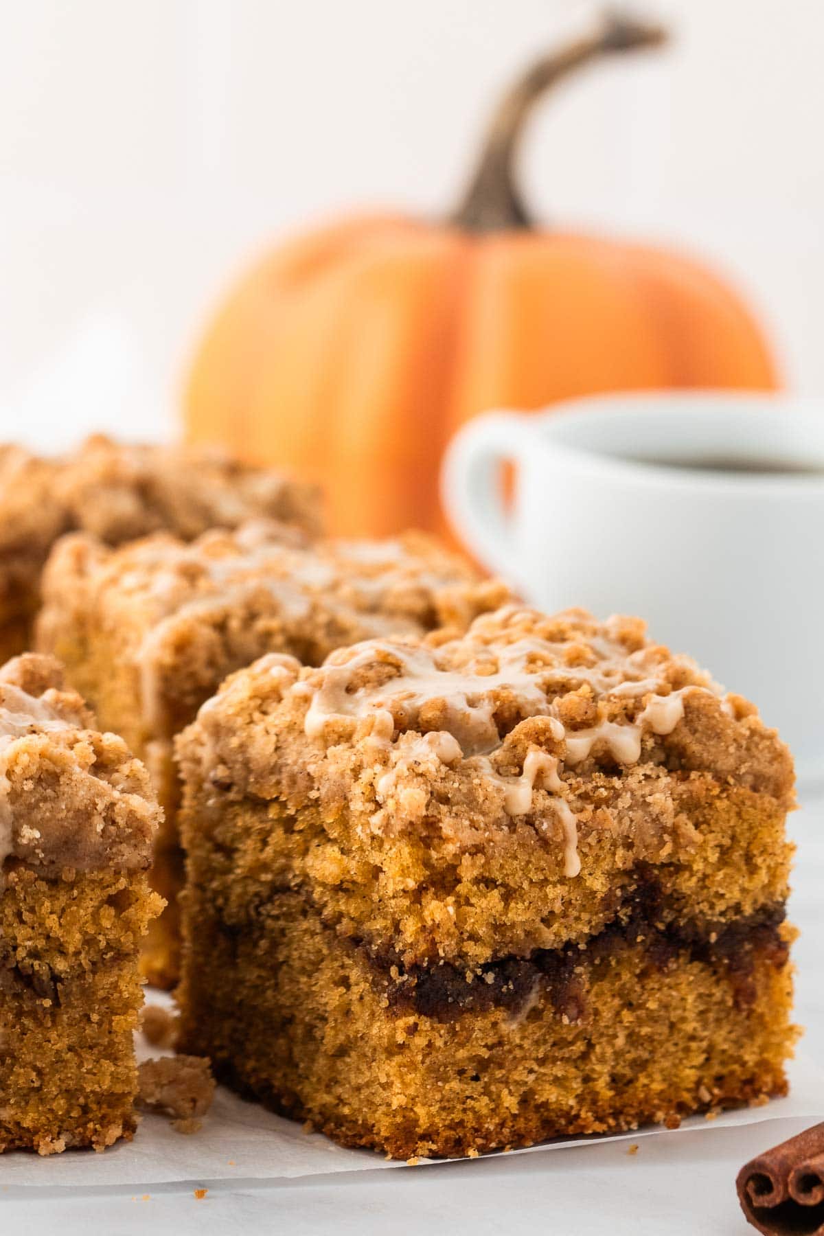Pumpkin coffee cake with a layer of cinnamon in the middle and a streusel and glaze topping.