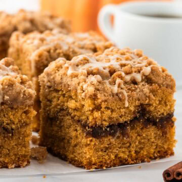 Side view of a slice of pumpkin coffee cake with a streusel and glaze on top.