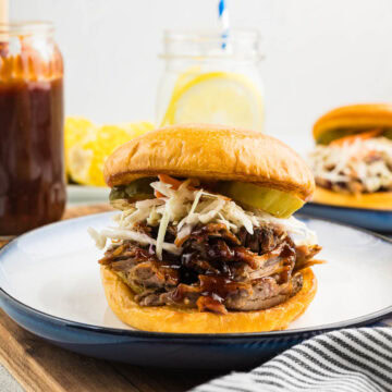 Pulled pork made in the slow cooker on a bun with pickles and barbecue sauce.
