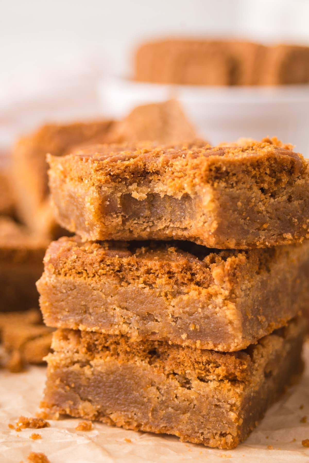 Three biscoff blondies stacked on top of each other with one with a bite taken out of it.