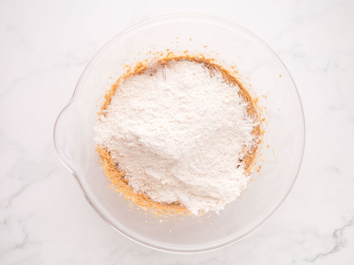 Adding the flour to the cookie dough in a large mixing bowl.
