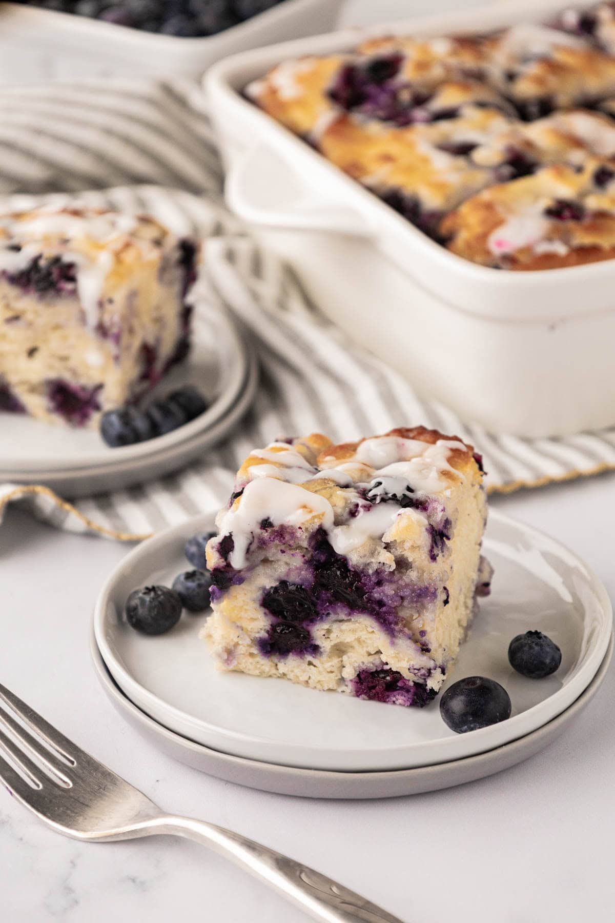 A slice of blueberry butter swim biscuit with the pan in the background