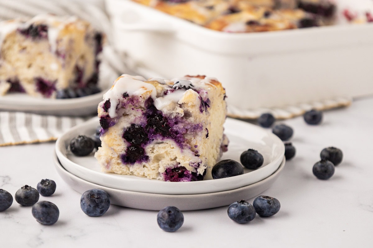A slice of blueberry butter swim biscuit with the pan in the background