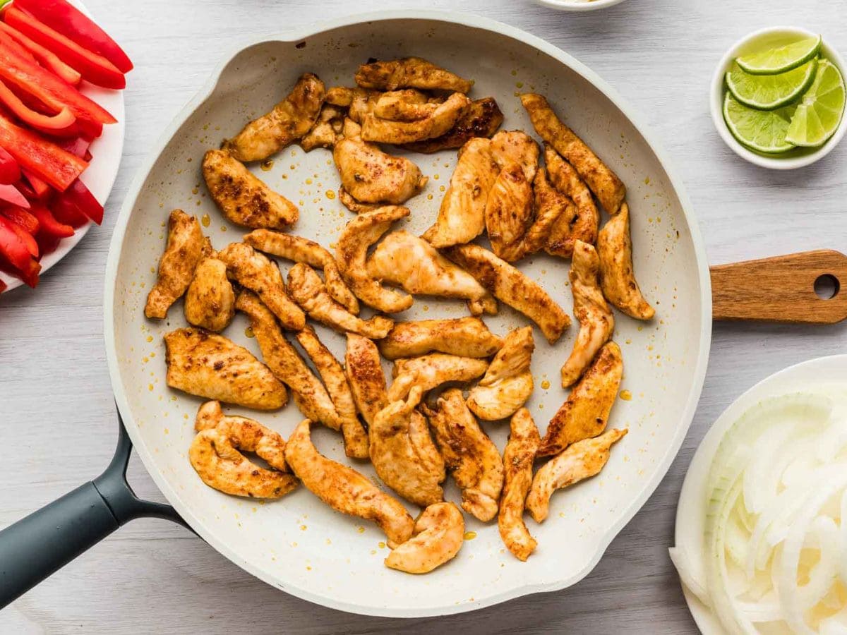 Chicken strips sautéing in a skillet.