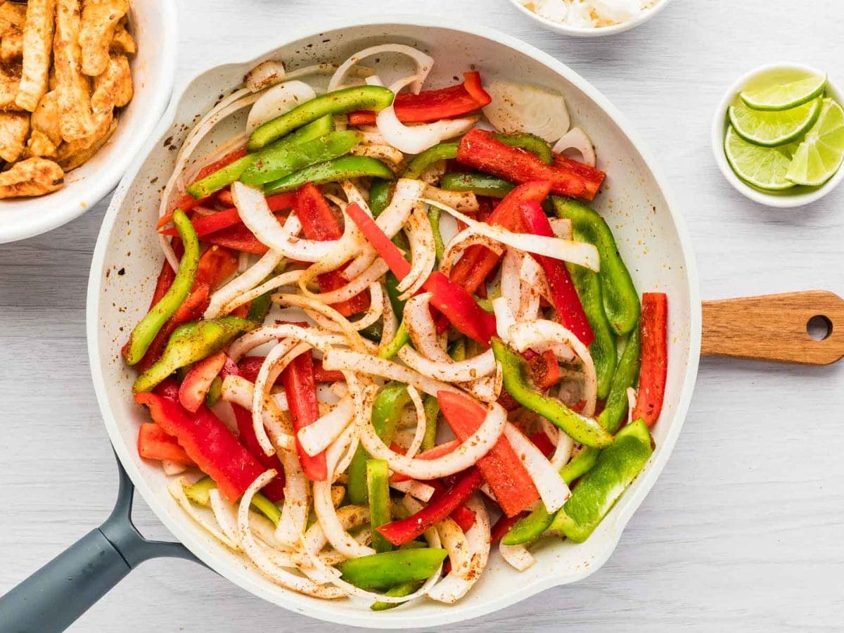 Fajita veggies sautéing in a skillet.
