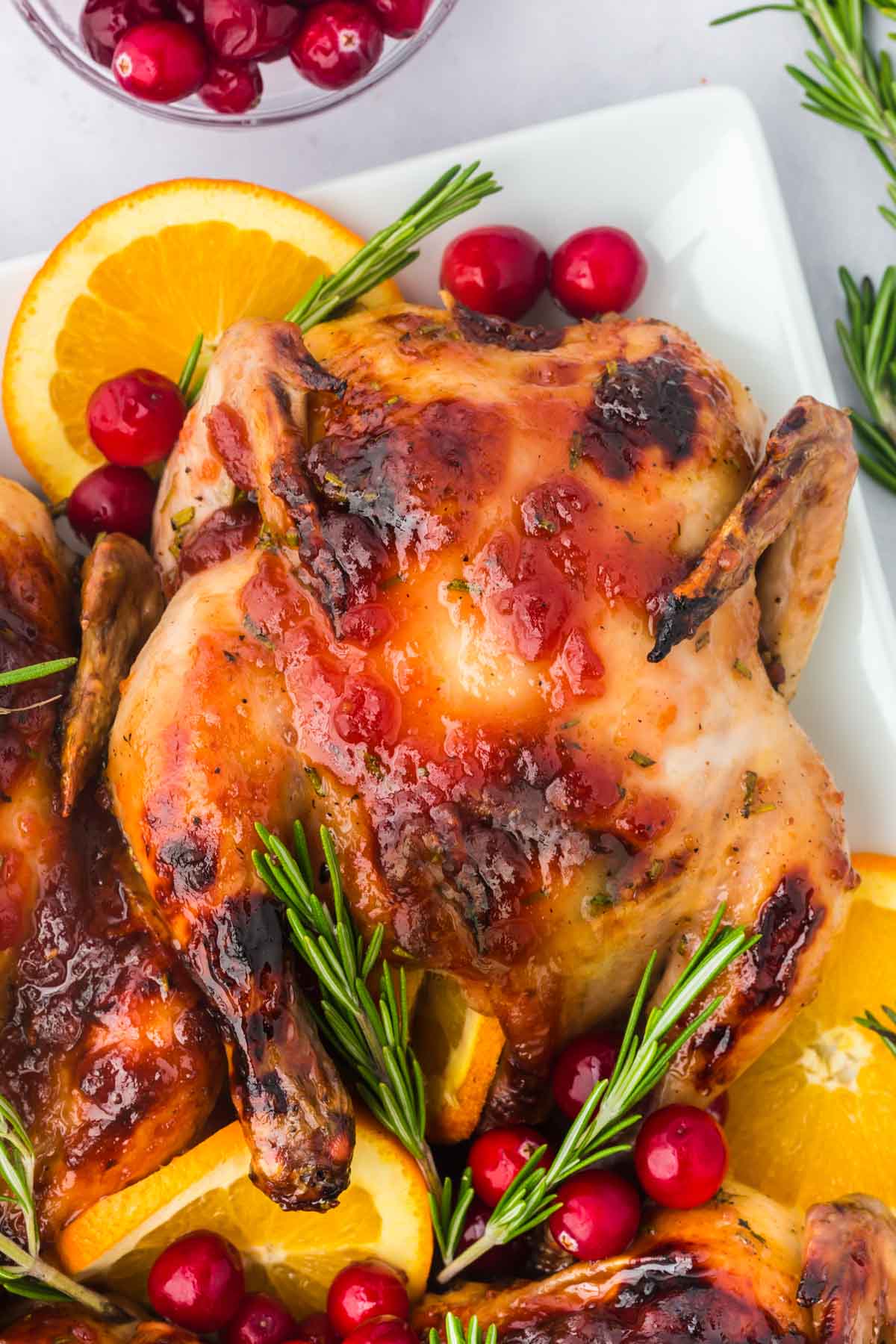 Close up of a cranberry orange glazed Cornish hen on a serving platter.