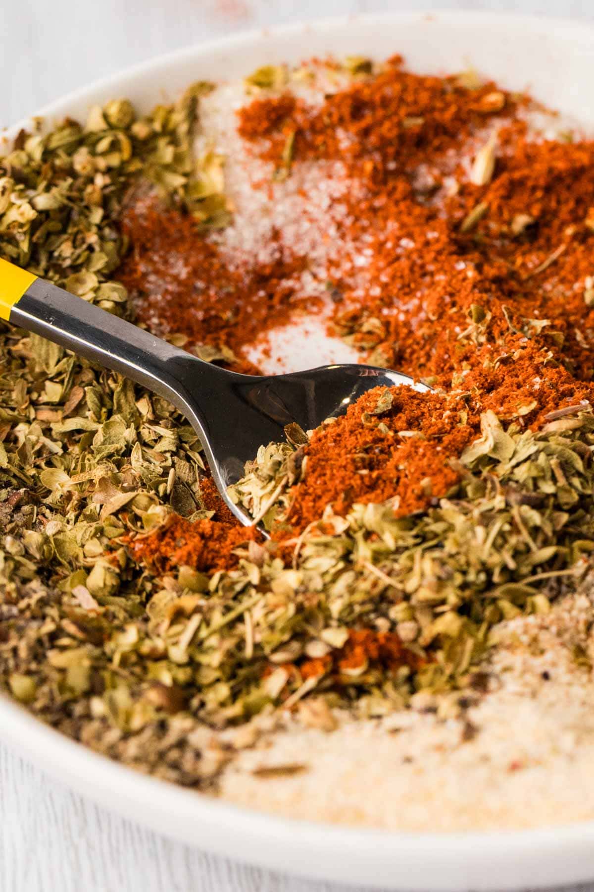 Close up of fajita seasoning in a bowl with a spoon scooping some up.